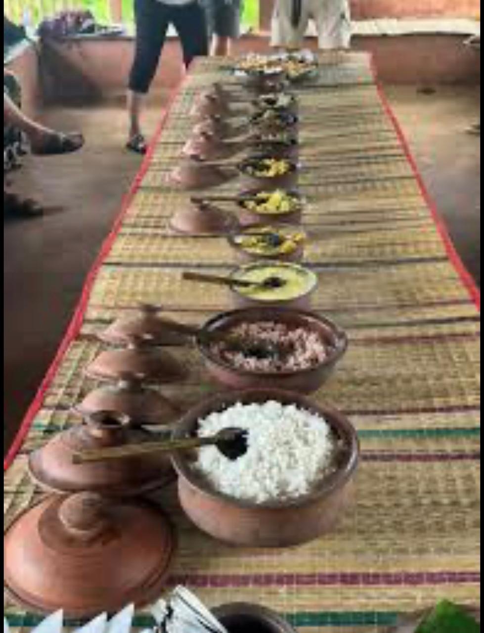 A long table set with clay pots of rice and curry on a woven mat, village-style
